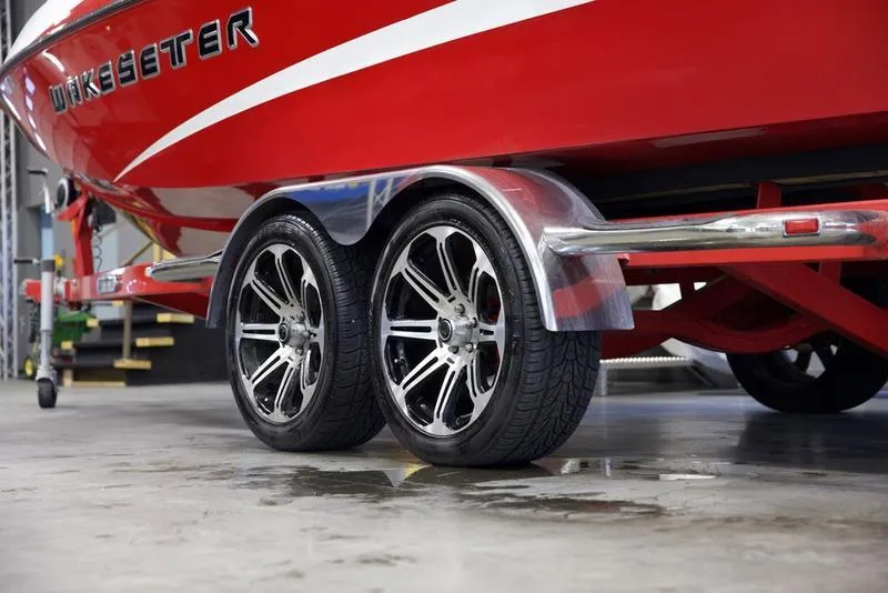 Slide: The Image of 2014 Malibu 247 LSV boat on trailer with shiny wheels in a garage. - 2