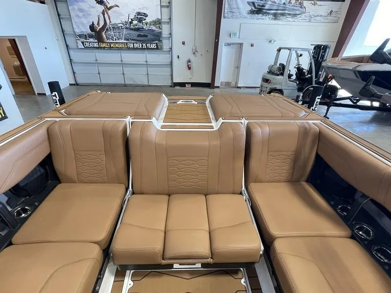Slide: The Image of 2025 Malibu 23 MXZ boat interior with tan leather seating in showroom. - 13