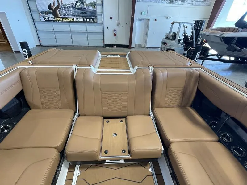 Slide: The Image of 2025 Malibu 23 MXZ boat interior with tan leather seating in showroom. - 14