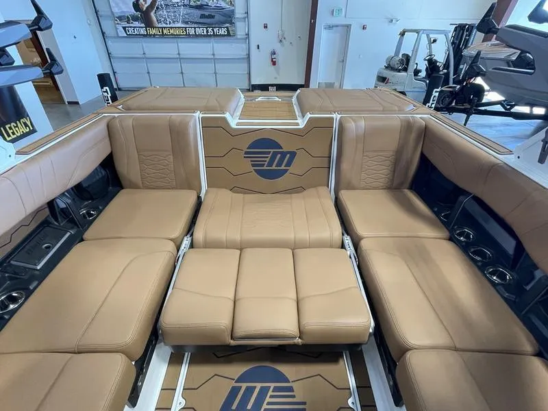 Slide: The Image of 2025 Malibu 23 MXZ boat interior with tan leather seating and logo design. - 15