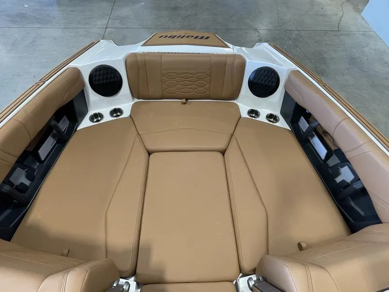 Slide: The Image of 2025 Malibu 23 MXZ boat interior with tan seating and built-in speakers. - 21