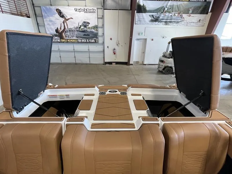 Slide: The Image of 2025 Malibu 23 MXZ boat interior with open storage compartments in a showroom. - 22