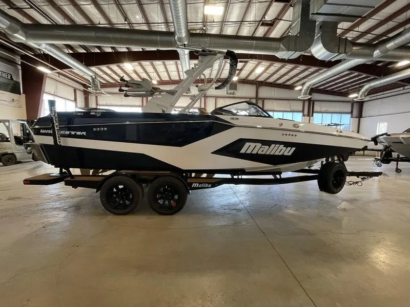 Slide: The Image of 2025 Malibu 23 MXZ boat in a warehouse, side view, on a trailer. - 24
