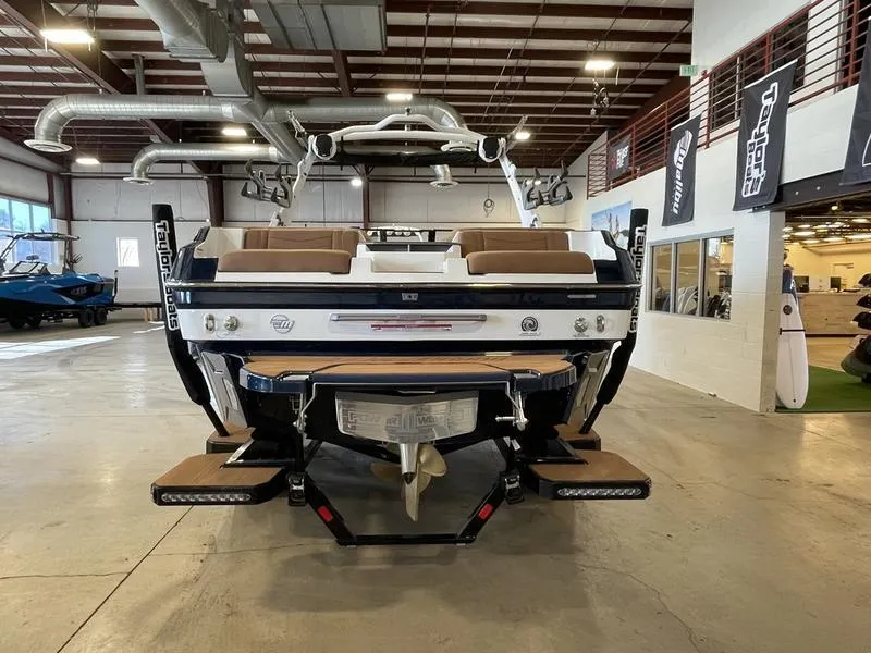 Slide: The Image of 2025 Malibu 23 MXZ boat in showroom, rear view with swim platform and seating. - 27