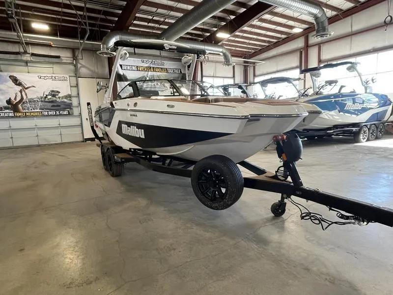 Slide: The Image of 2025 Malibu 23 MXZ boat in showroom, on trailer, with sleek design and modern features. - 4