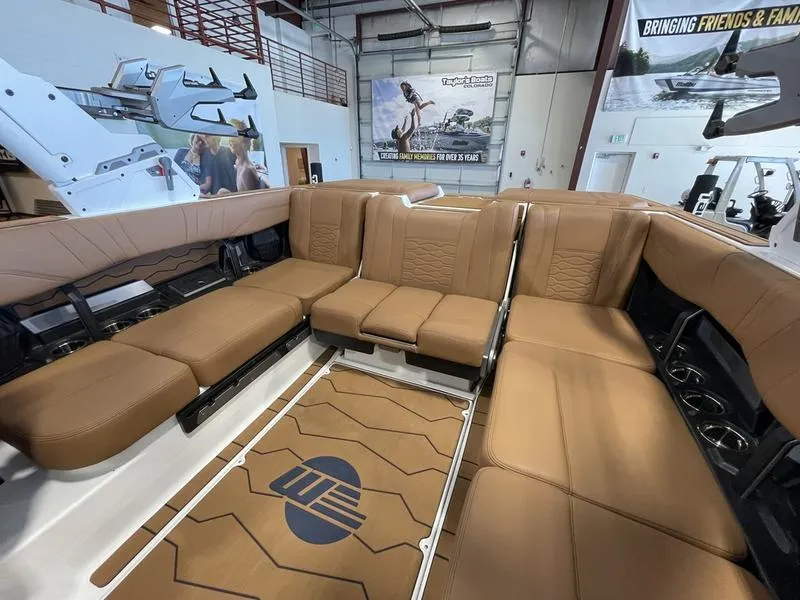 Slide: The Image of 2025 Malibu 23 MXZ boat interior with luxurious brown seating in a showroom. - 8