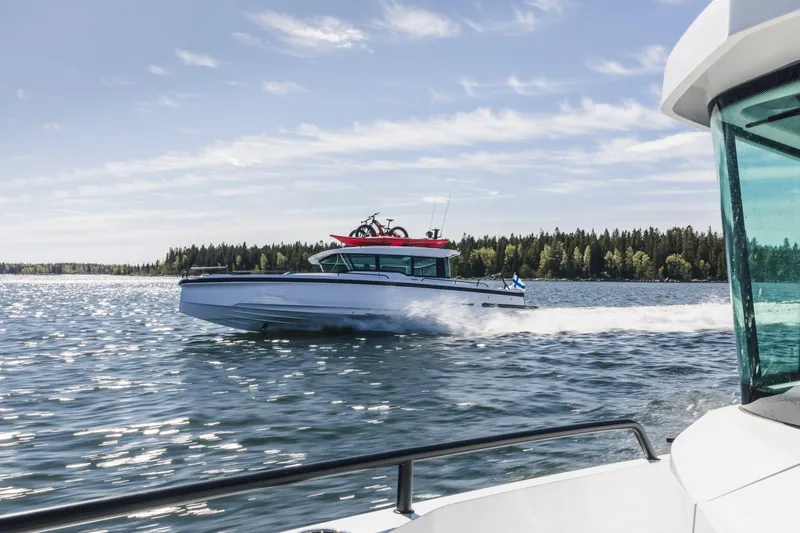 Slide: The Image of 2024 Axopar 37 XC Cross Cabin BRABUS Trim cruising near waterfront homes. - 3