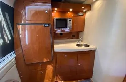 Slide: The Image of 2006 Regal Commodore 3560 IO yacht kitchen with wood cabinets, microwave, and sink. - 17