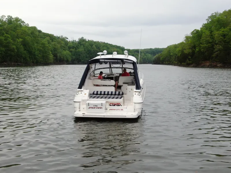 Slide: The Image of 2006 Regal Commodore 3560 IO cruising on a serene lake surrounded by lush greenery. - 24