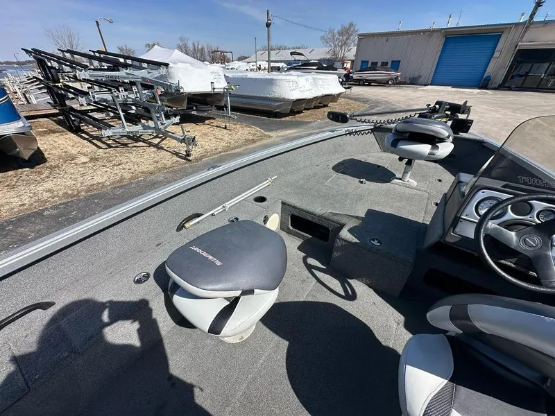 Slide: The Image of 2014 Alumacraft Competitor 175 CS boat interior with seats and steering wheel, parked outdoors. - 12