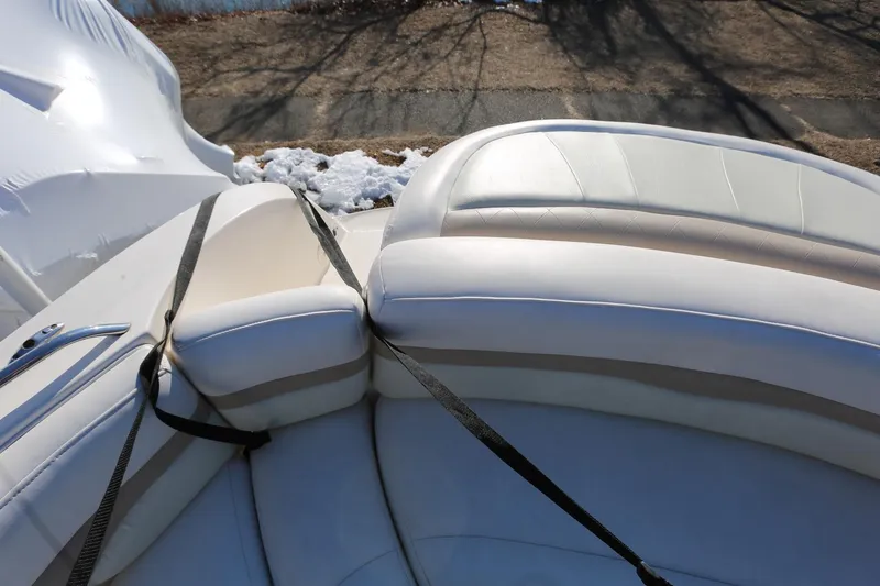 Slide: The Image of 2005 Chaparral 236 Sunesta boat interior with white cushioned seating and safety straps. - 10