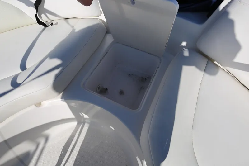 Slide: The Image of 2005 Chaparral 236 Sunesta boat interior storage compartment with white seating. - 22