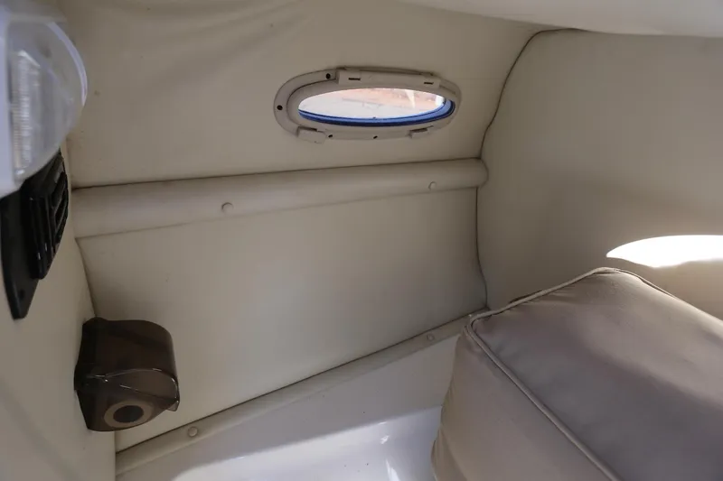Slide: The Image of Interior cabin of 2005 Chaparral 236 Sunesta boat, featuring a small window and seating area. - 24