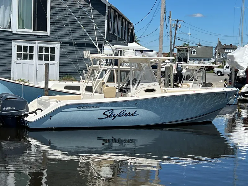 The Image of 2014 Cobia 296 Center Console boat docked, featuring sleek design and Yamaha engine. - 14