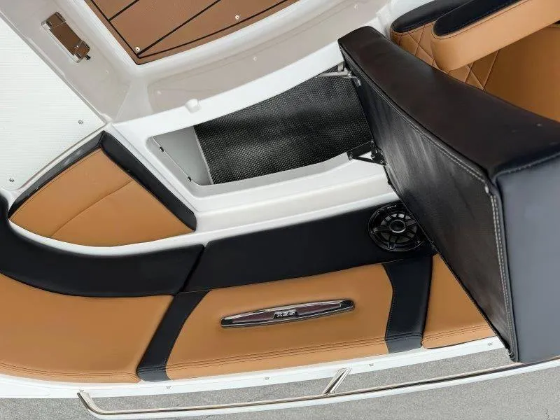 Slide: The Image of 2022 Chaparral 287 SSX boat interior with tan and black seating, storage compartment. - 38