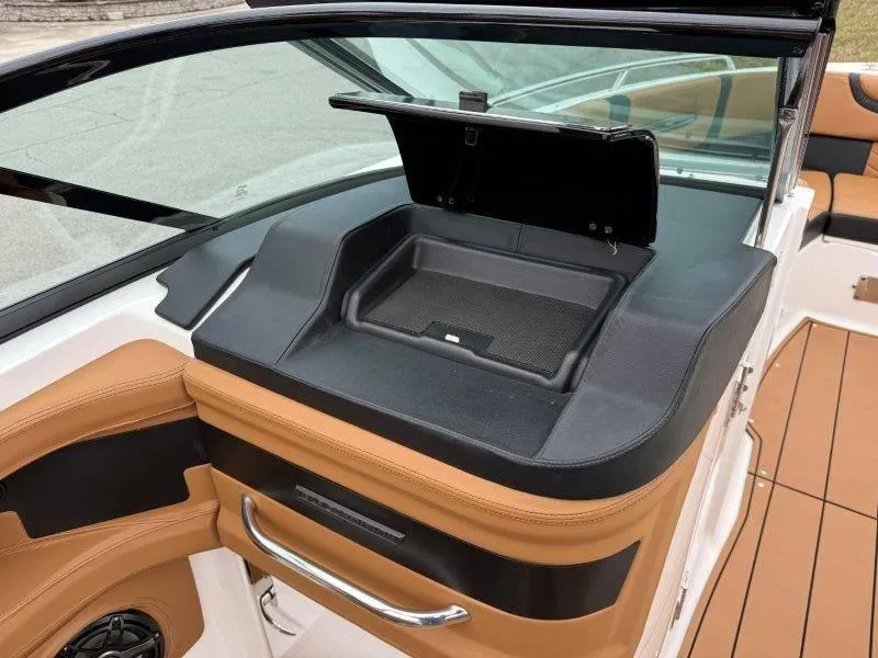 Slide: The Image of 2022 Chaparral 287 SSX boat interior with open storage compartment and tan seating. - 9