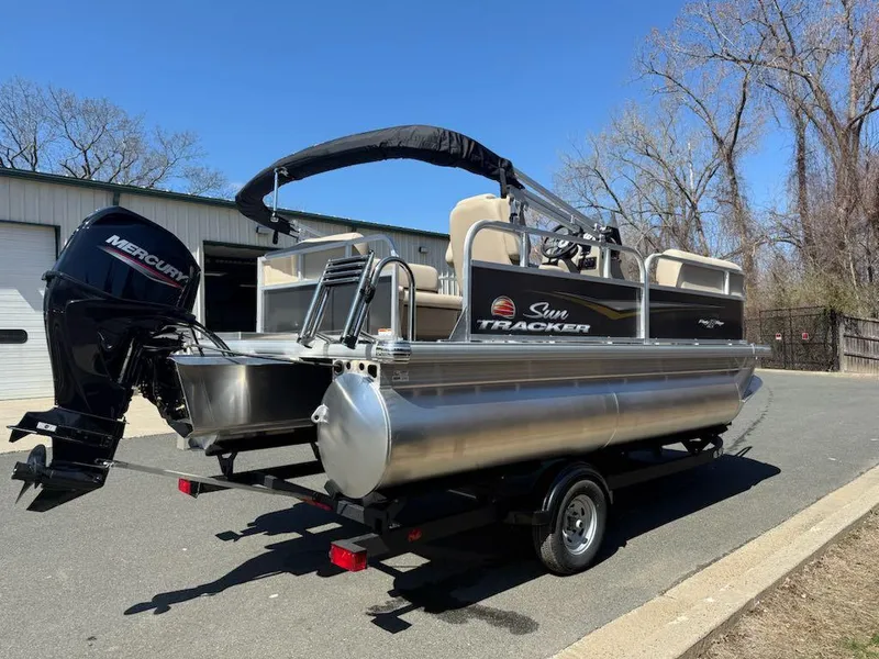 Slide: The Image of 2025 Sun Tracker Party Barge 16 DLX pontoon boat on trailer, parked outdoors. - 3