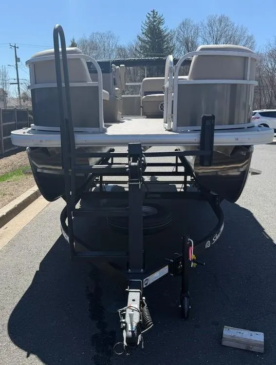 Slide: The Image of 2025 Sun Tracker Party Barge 16 DLX pontoon boat on trailer, parked outdoors. - 47