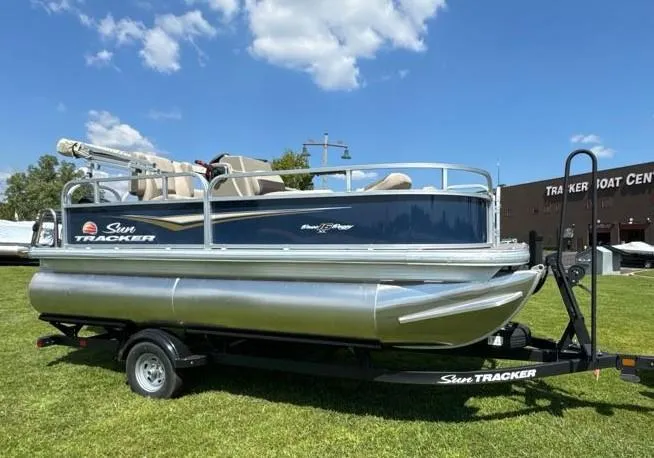 Slide: The Image of 2025 Sun Tracker Bass Buggy 16 XL Select pontoon boat on trailer, outdoors. - 4