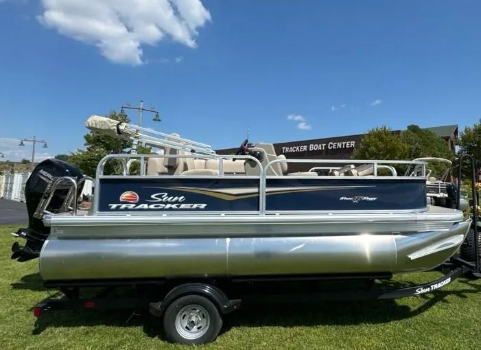 Slide: The Image of 2025 Sun Tracker Bass Buggy 16 XL Select pontoon boat on trailer, outdoors. - 5