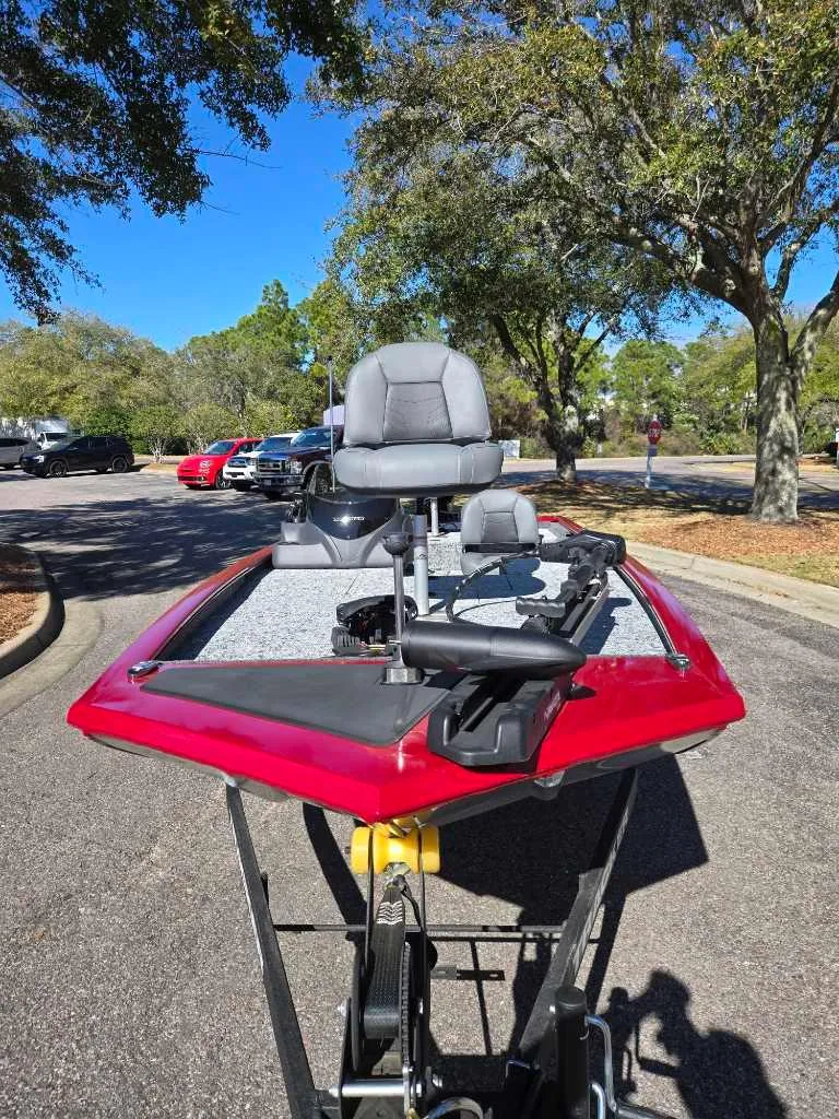 Slide: The Image of 2025 Tracker Pro 170 boat with red exterior, parked outdoors on a sunny day. - 2