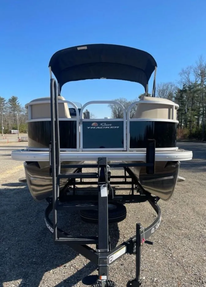 Slide: The Image of 2025 Sun Tracker Party Barge 16 DLX pontoon boat on trailer, parked outdoors. - 2