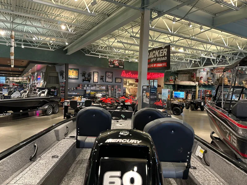 Slide: The Image of 2025 Tracker Pro Guide V-16 SC boat displayed in a showroom with various marine equipment. - 2