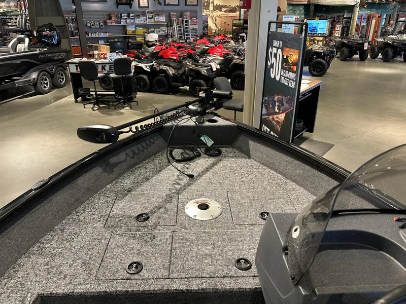 Slide: The Image of 2025 Tracker Pro Guide V-16 SC boat interior in showroom with various vehicles displayed. - 3