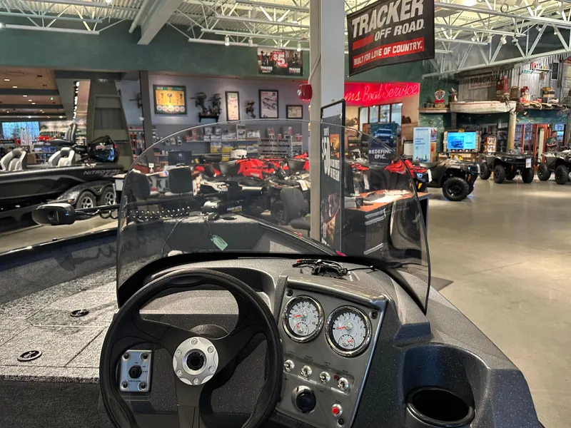 Slide: The Image of 2025 Tracker Pro Guide V-16 SC boat dashboard in showroom with steering wheel and gauges. - 4