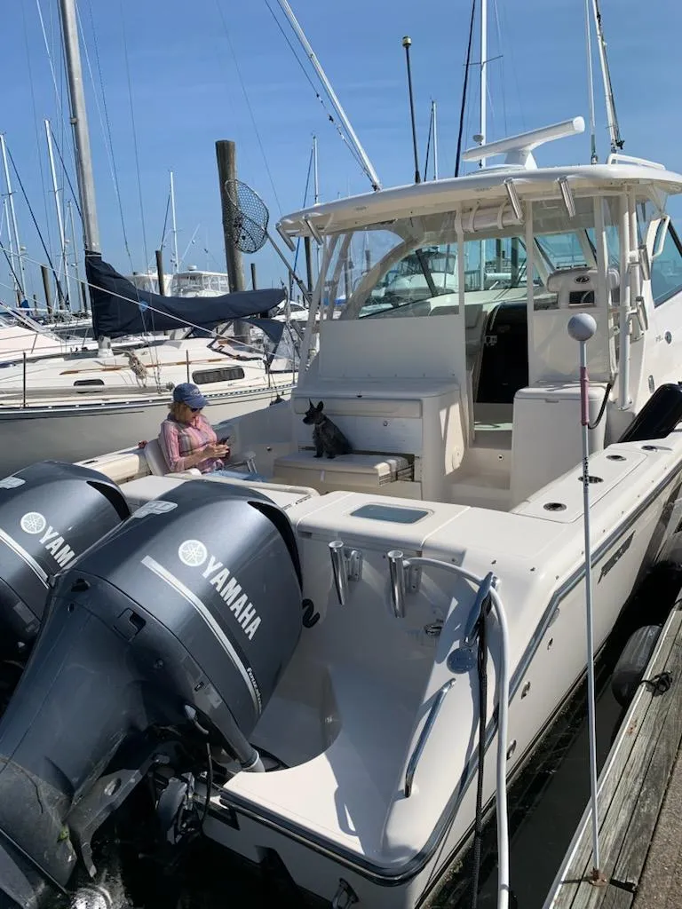 Slide: The Image of 2014 Pursuit OS 345 Offshore boat docked, featuring dual Yamaha engines, with a person seated onboard. - 15