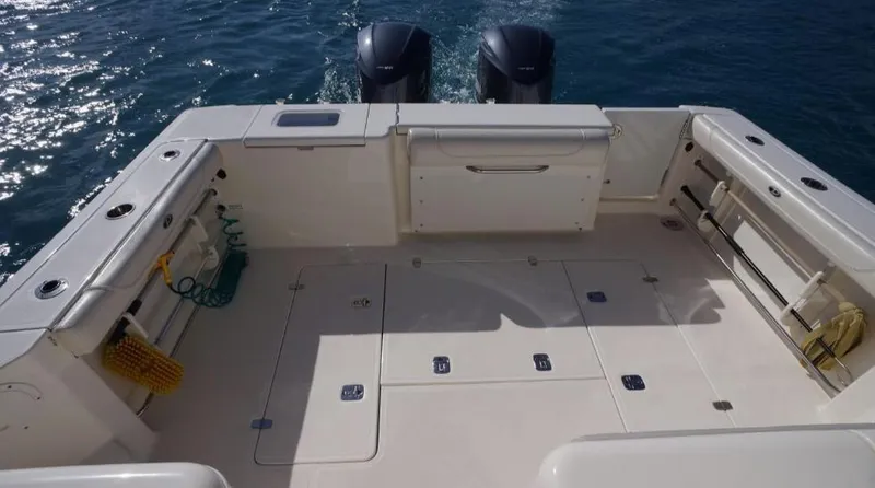 Slide: The Image of 2014 Pursuit OS 345 Offshore boat deck with dual engines, spacious layout, and storage compartments. - 17