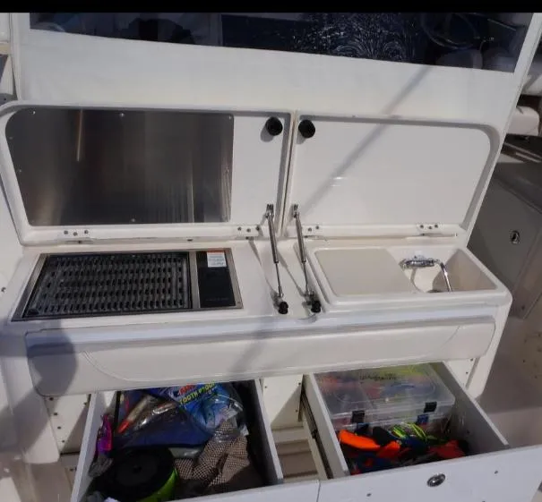 Slide: The Image of 2014 Pursuit OS 345 Offshore boat kitchen with grill, sink, and storage drawers. - 20
