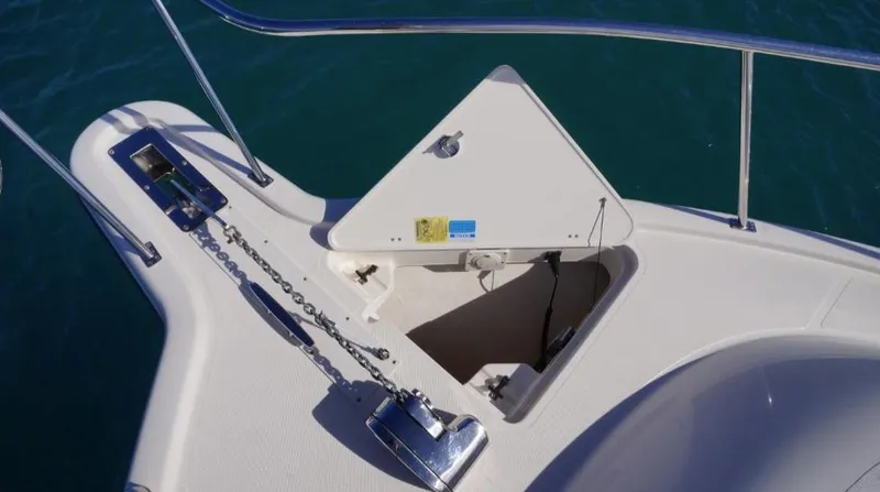 Slide: The Image of 2014 Pursuit OS 345 Offshore boat anchor compartment with chain, on calm blue water. - 25