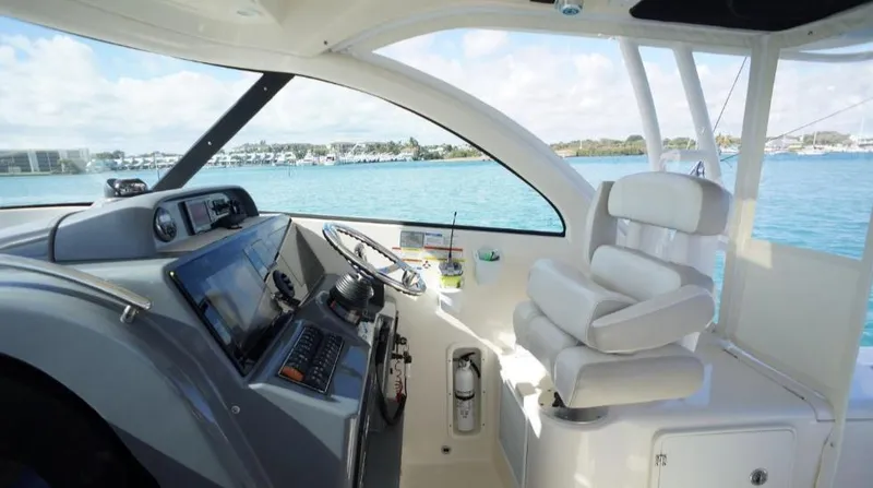 Slide: The Image of 2014 Pursuit OS 345 Offshore helm with modern controls and comfortable seating, overlooking serene waters. - 27