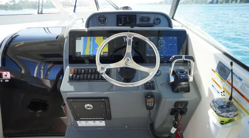 Slide: The Image of 2014 Pursuit OS 345 Offshore helm with navigation screens and controls on a sunny day. - 28