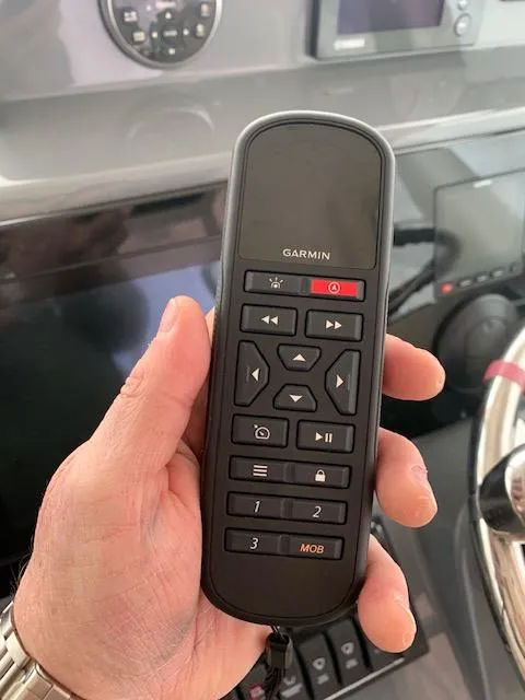 Slide: The Image of Hand holding Garmin remote control on 2014 Pursuit OS 345 Offshore boat dashboard. - 47