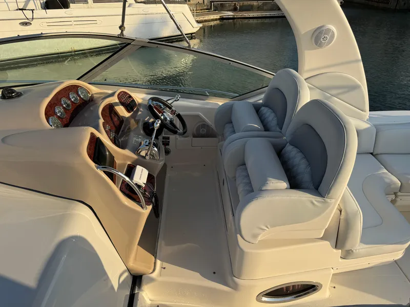 Slide: The Image of 2005 Sea Ray 340 Sundancer cockpit with dual seats and control panel, docked by water. - 44