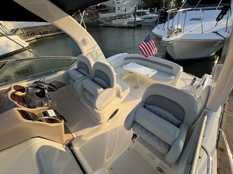 Slide: The Image of 2005 Sea Ray 340 Sundancer yacht interior with seating, helm, and American flag at marina. - 45