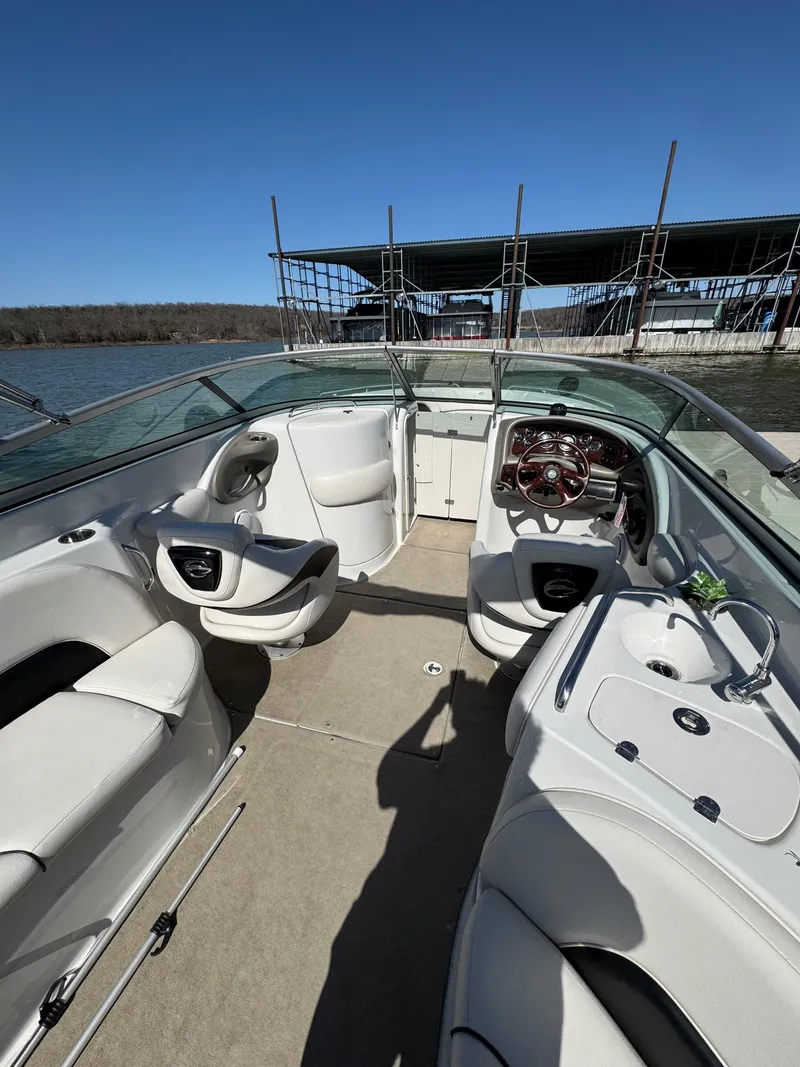 Slide: The Image of 2008 Crownline 270 BR boat interior with seating and steering wheel, docked by the water. - 10