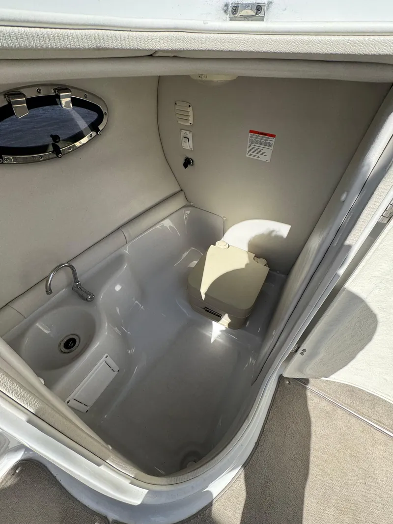 Slide: The Image of 2008 Crownline 270 BR boat interior with sink and portable toilet. - 11