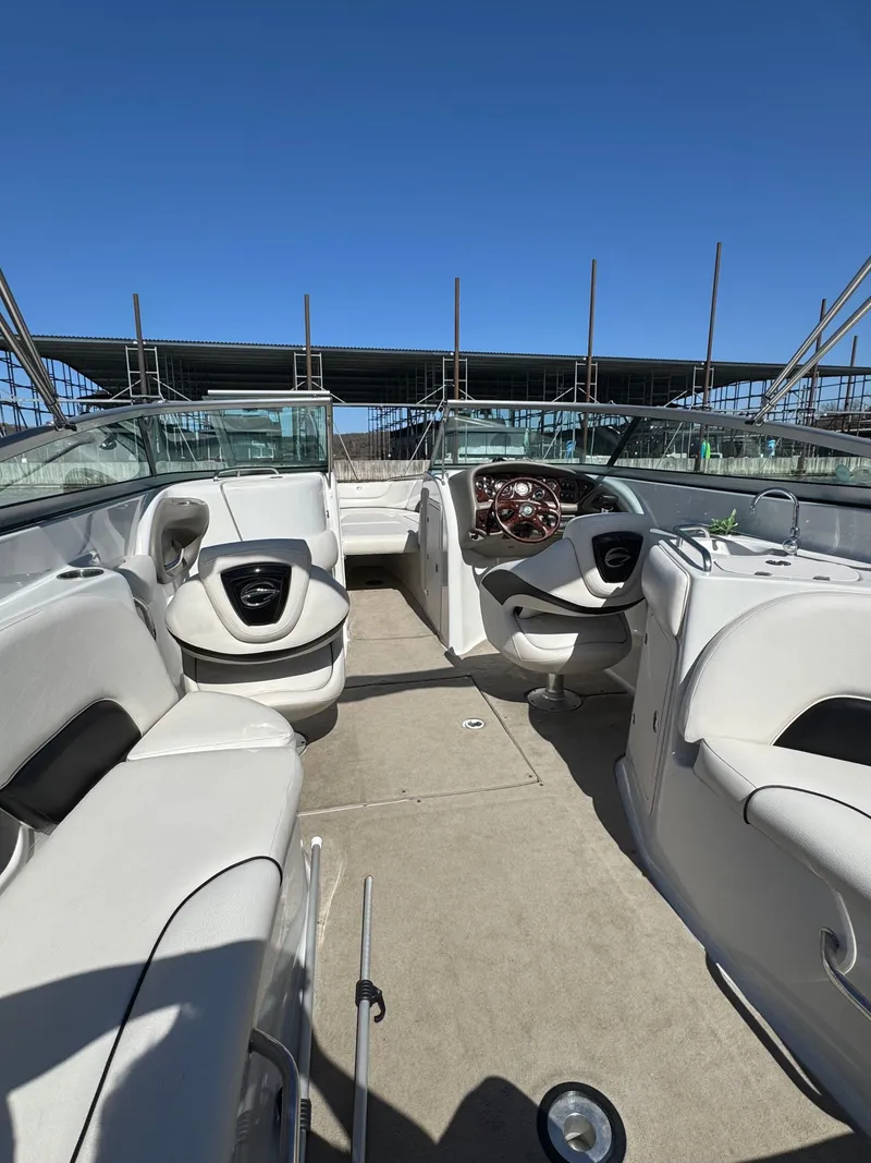 Slide: The Image of 2008 Crownline 270 BR boat interior with white seating and steering wheel under clear blue sky. - 2