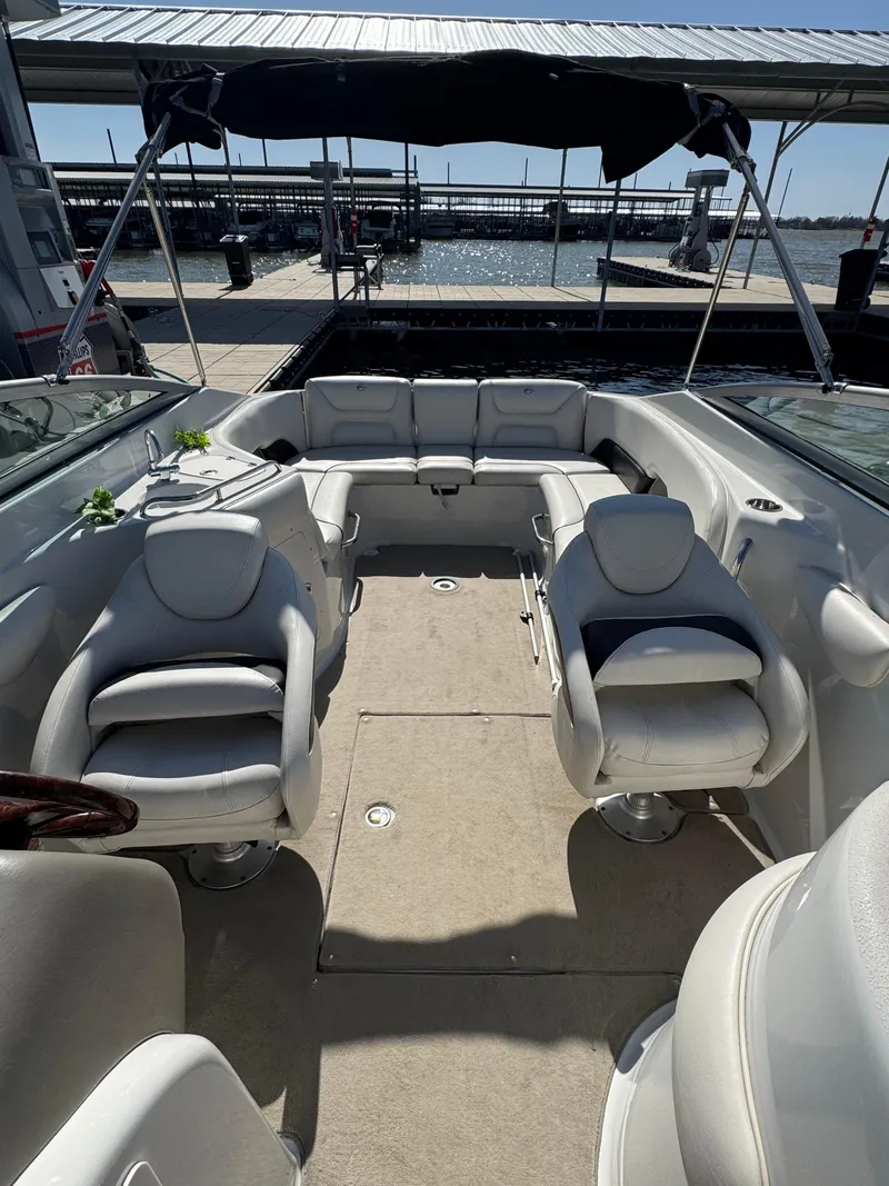 Slide: The Image of 2008 Crownline 270 BR boat interior with white seating and canopy at dock. - 3