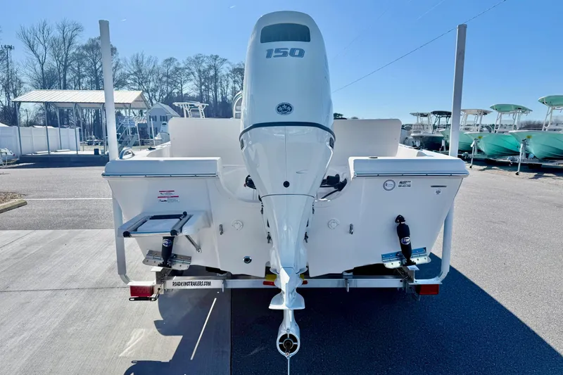 The Image of 2025 Carolina Skiff 21 Ultra Elite boat on trailer at dealership, blue and white design. - 1