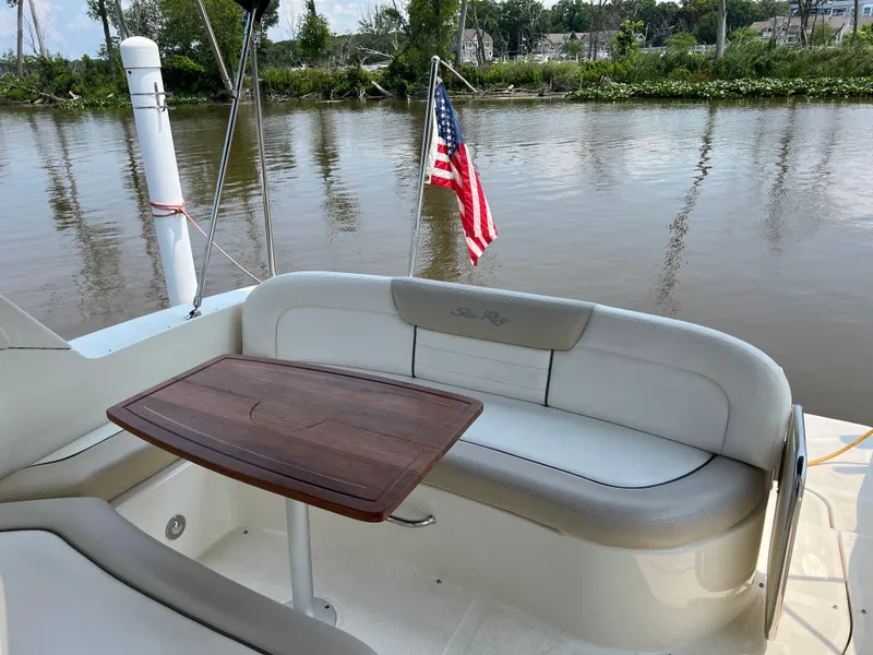 Slide: The Image of 2011 Sea Ray 330 Sundancer boat with seating area and table, American flag in background. - 13