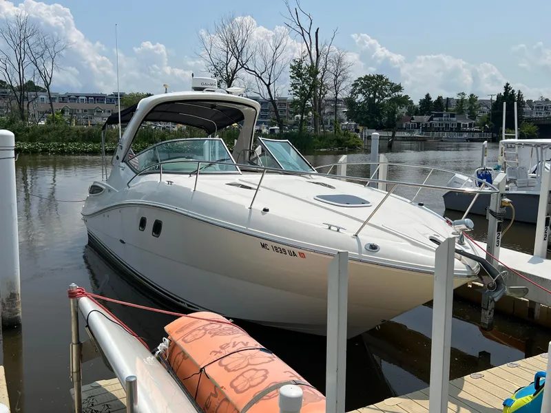 Slide: The Image of 2011 Sea Ray 330 Sundancer docked in a marina, surrounded by calm water and trees. - 2
