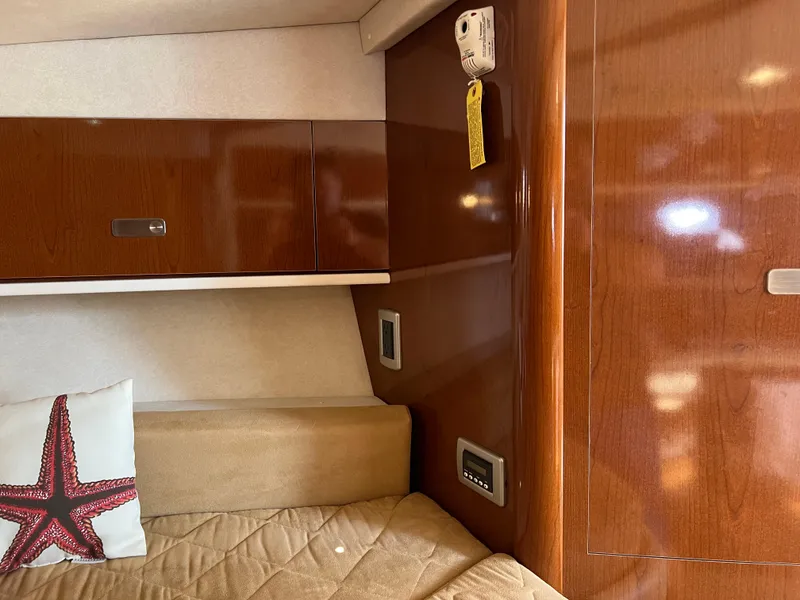 Slide: The Image of 2011 Sea Ray 330 Sundancer cabin interior with wood finish and starfish pillow. - 23