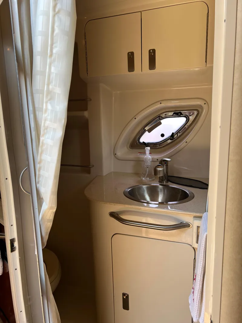 Slide: The Image of 2011 Sea Ray 330 Sundancer bathroom with sink, cabinet, and porthole window. - 31