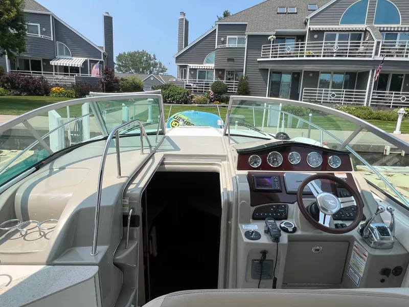 Slide: The Image of 2011 Sea Ray 330 Sundancer boat cockpit with modern controls, docked near waterfront homes. - 4