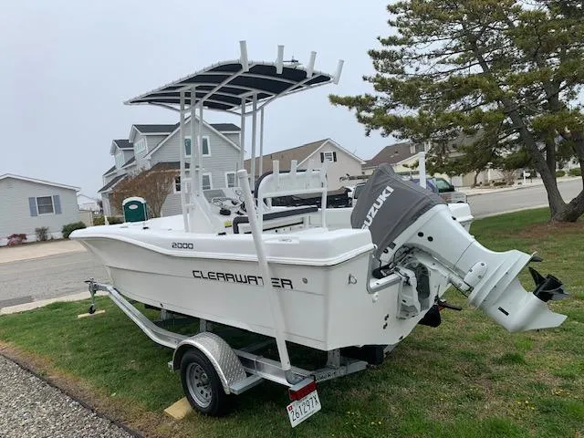 Slide: The Image of 2022 Clearwater 2000CC boat on trailer with Suzuki outboard motor, parked in residential area. - 2