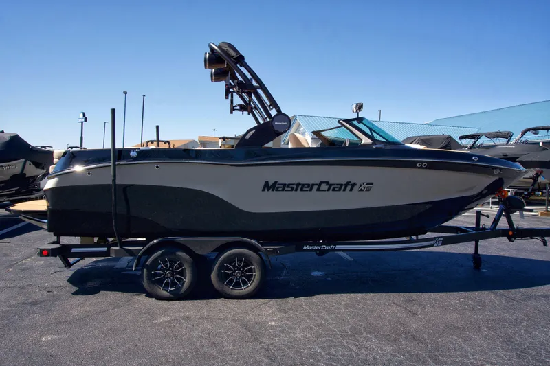 The Image of 2025 MasterCraft XT23 boat on trailer, parked outdoors, side view. - 0